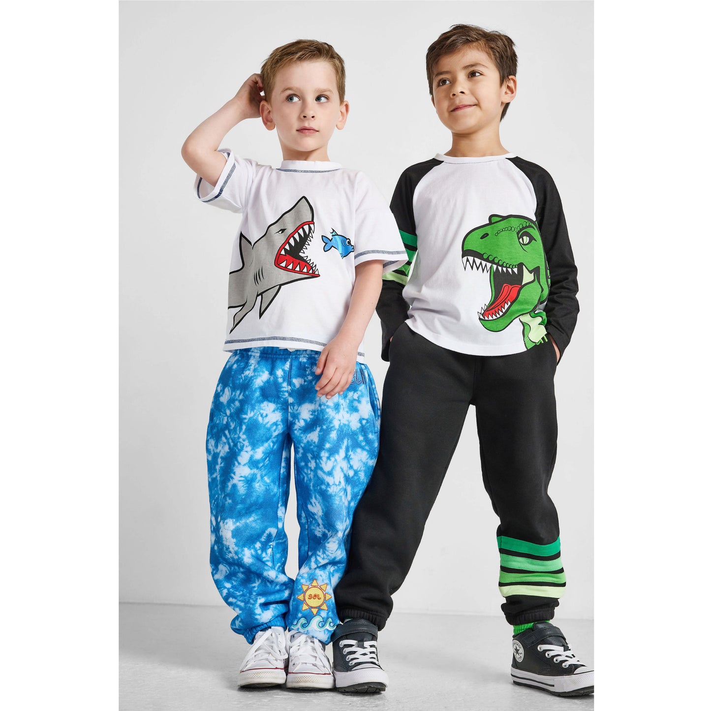 boys wearing our sustainable shark tee with blue tie-dye ocean pants, and dinosaur baseball tee with green striped joggers