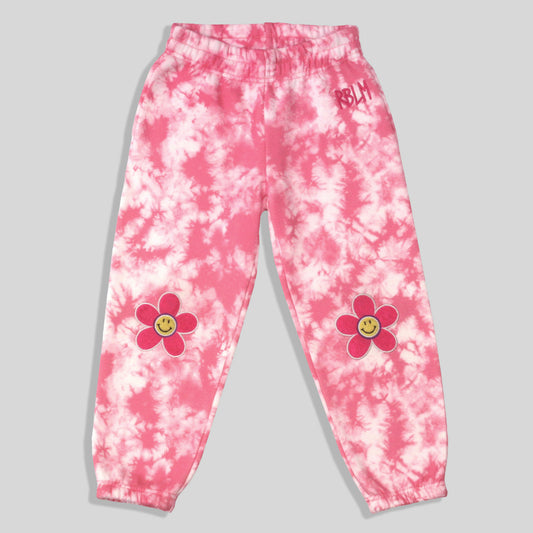 Sustainable, fun, and comfortable pink and white tie-dye sweatpants for kids with pink flower graphics featuring yellow smiley faces on each knee, and a small pink 'RBLM' graphic on the right hip.