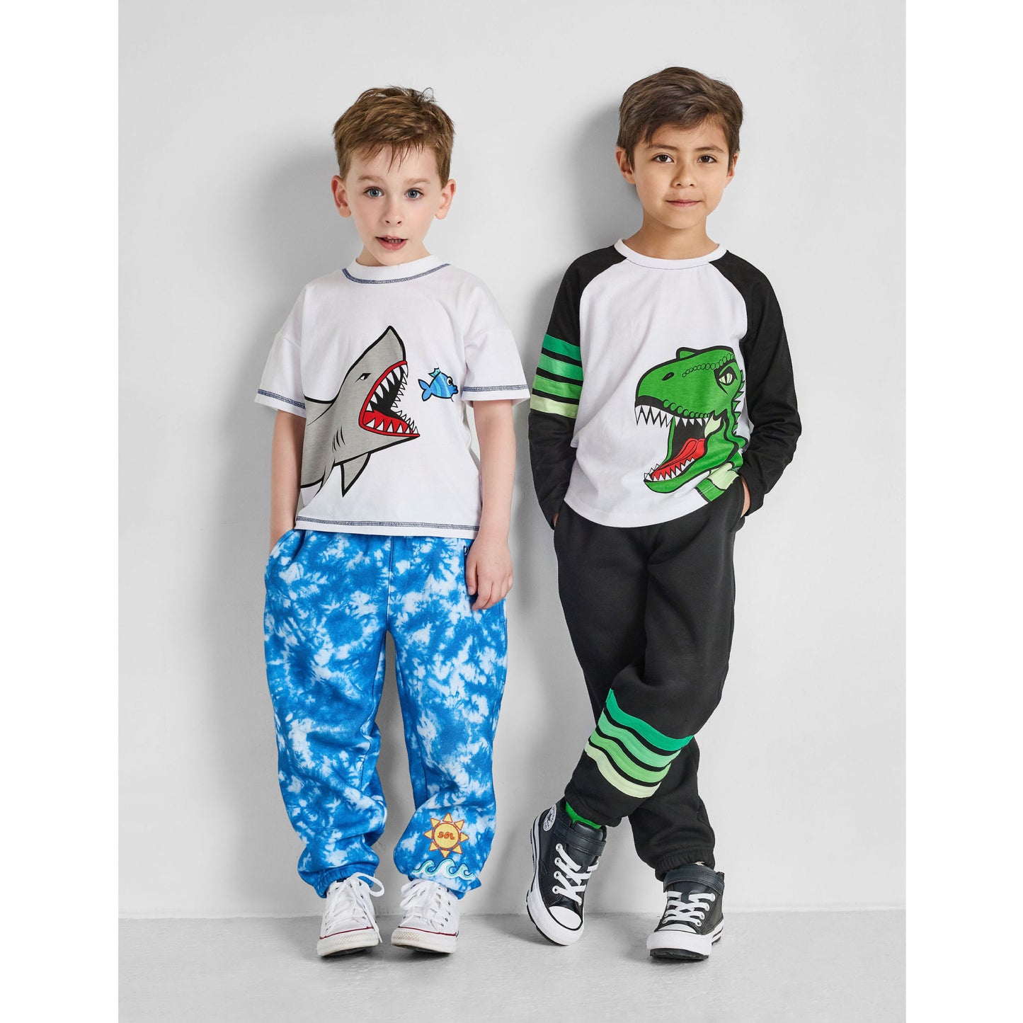 boys wearing our sustainable shark tee with blue tie-dye ocean pants, and dinosaur baseball tee with green striped joggers