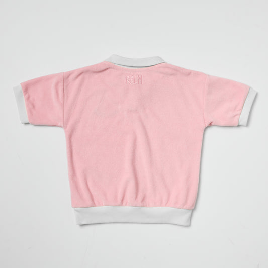 Eco-friendly kids pink terry polo with white trim on a light gray background
