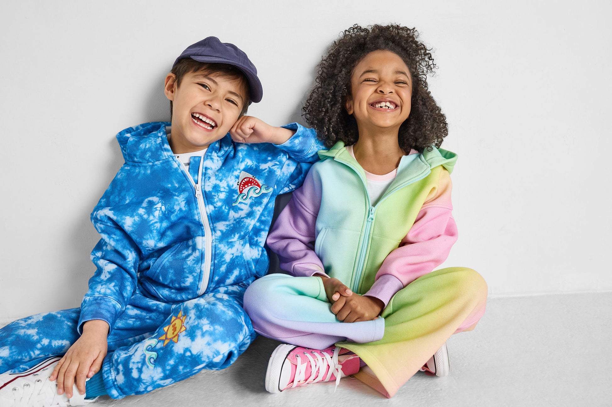 kids smiling wearing our sustainable rainbow wide-leg jogger and shark tie-dye sets