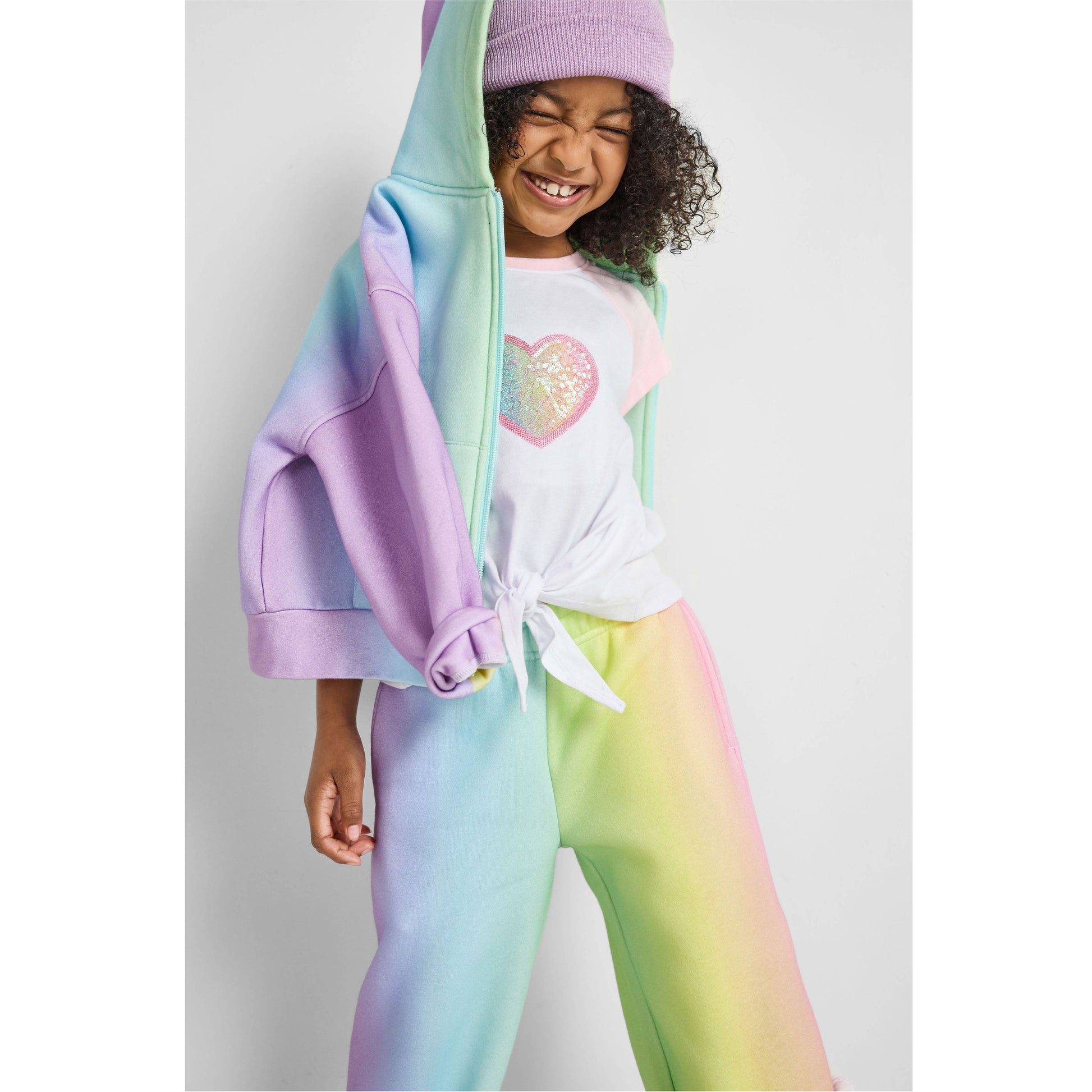 girl wearing our sustainable rainbow wide-leg jogger set and heart knotted baseball tee