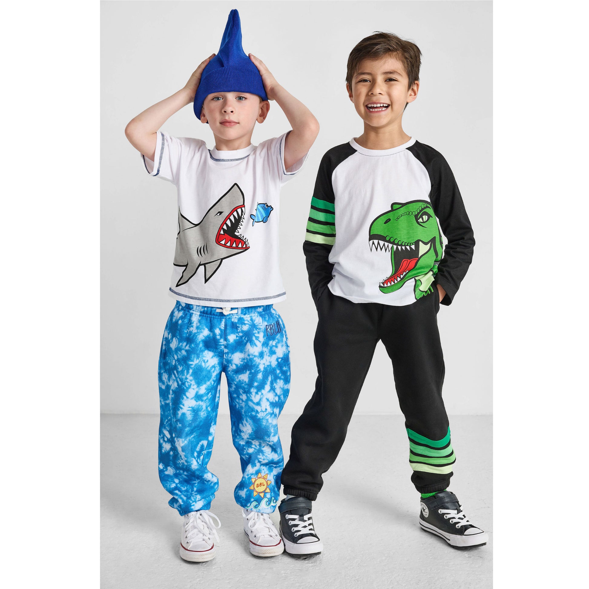boys wearing our sustainable shark tee with blue tie-dye ocean pants, and dinosaur baseball tee with green striped joggers