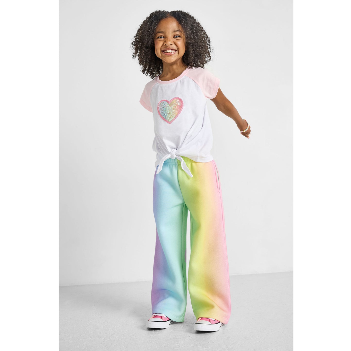 girl wearing our sustainable heart knotted baseball tee with rainbow wide-leg joggers