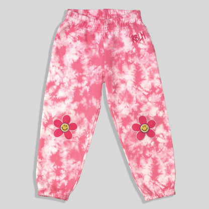 Sustainable, fun, and comfortable pink and white tie-dye sweatpants for kids with pink flower graphics featuring yellow smiley faces on each knee, and a small pink 'RBLM' graphic on the right hip.