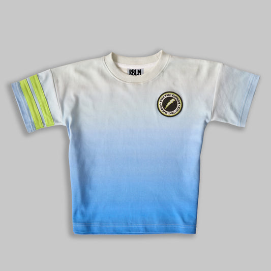 A sustainable, comfortable, and fun t-shirt for children, featuring a white-to-blue ombré pattern with a black and green lightning patch on the left chest and two green stripes on the right sleeve.