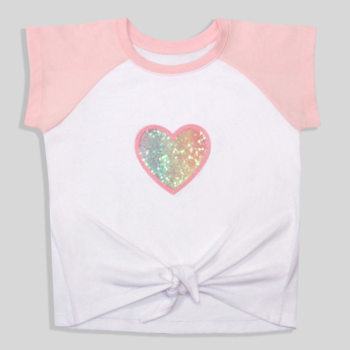 A sustainable, colorful, and comfortable white and pink raglan t-shirt with a knotted hem, featuring a recycled sequined and embroidered heart graphic on the chest.