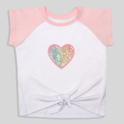 A sustainable, colorful, and comfortable white and pink raglan t-shirt with a knotted hem, featuring a recycled sequined and embroidered heart graphic on the chest.