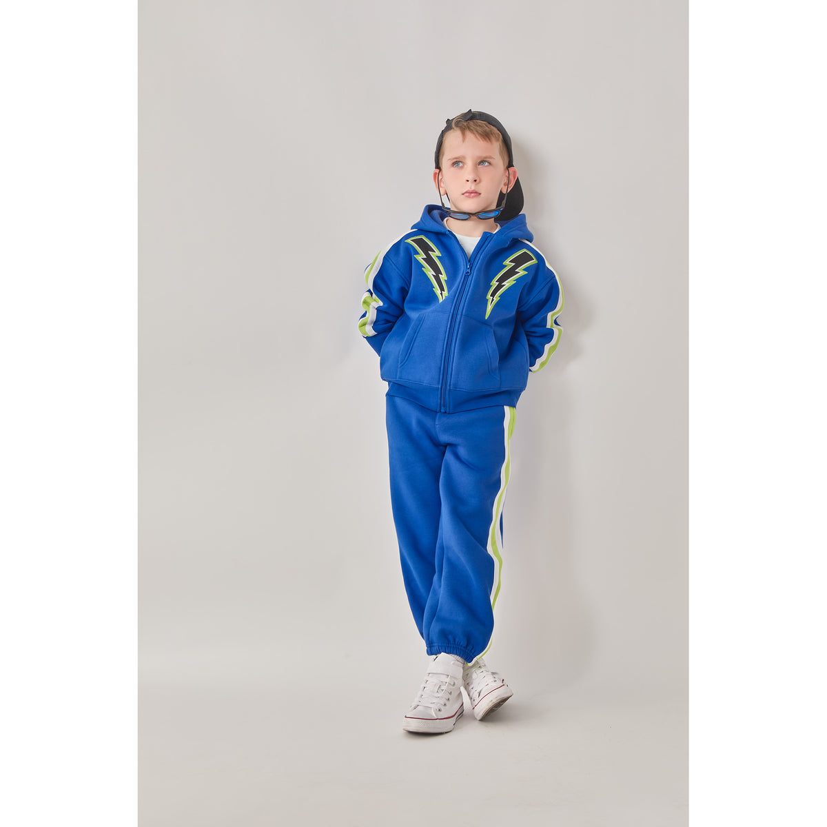 A boy wearing an eco-friendly blue lightning hooded sweatshirt and sweatpants.