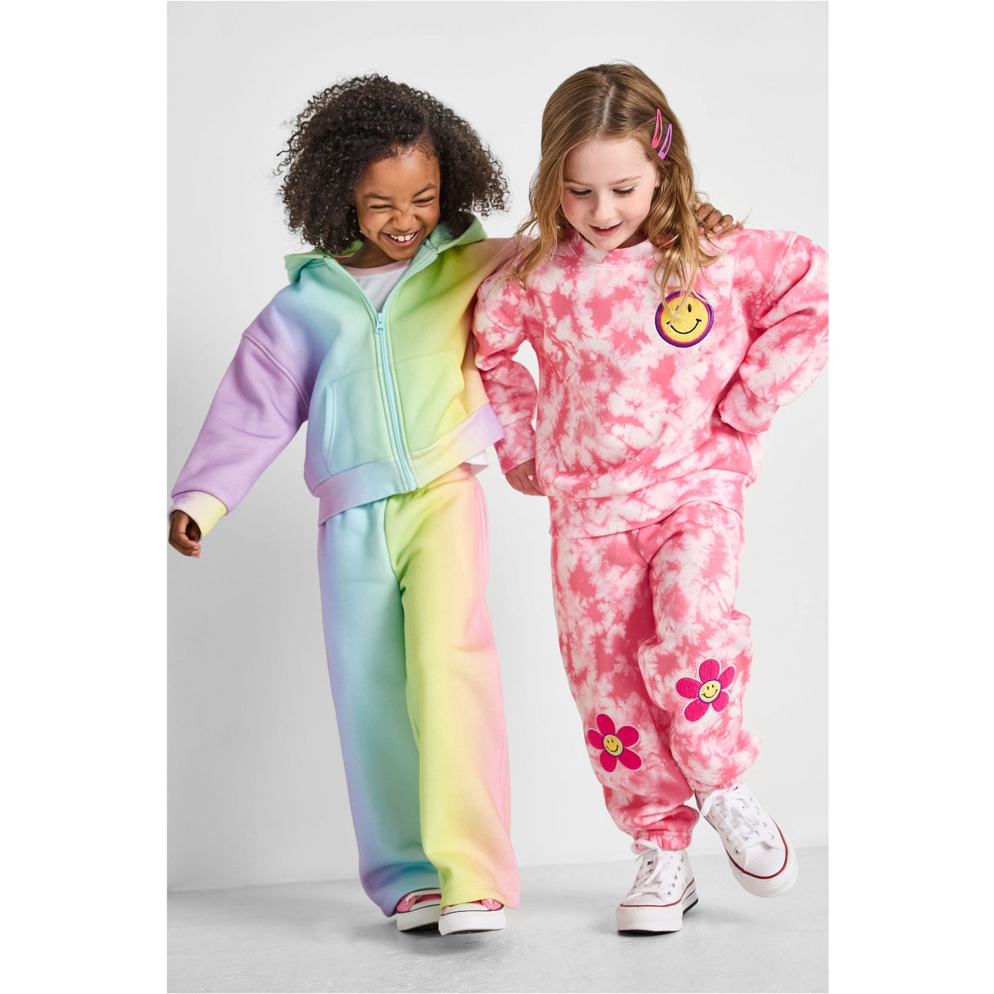 walking girls wearing our eco-friendly rainbow wide-leg jogger set and smiley tie-dye jogger set
