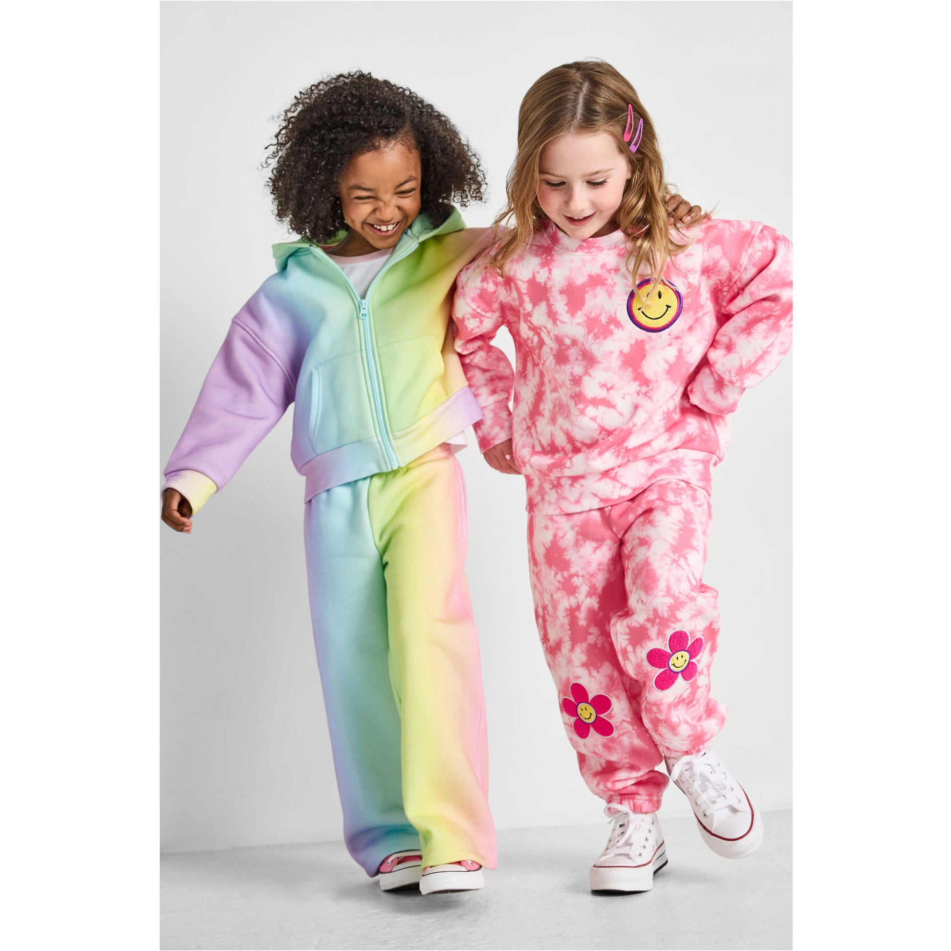 walking girls wearing our eco-friendly rainbow wide-leg jogger set and smiley tie-dye jogger set