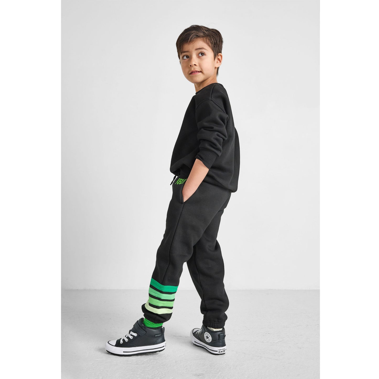 side view of boy wearing our eco-friendly green striped joggers