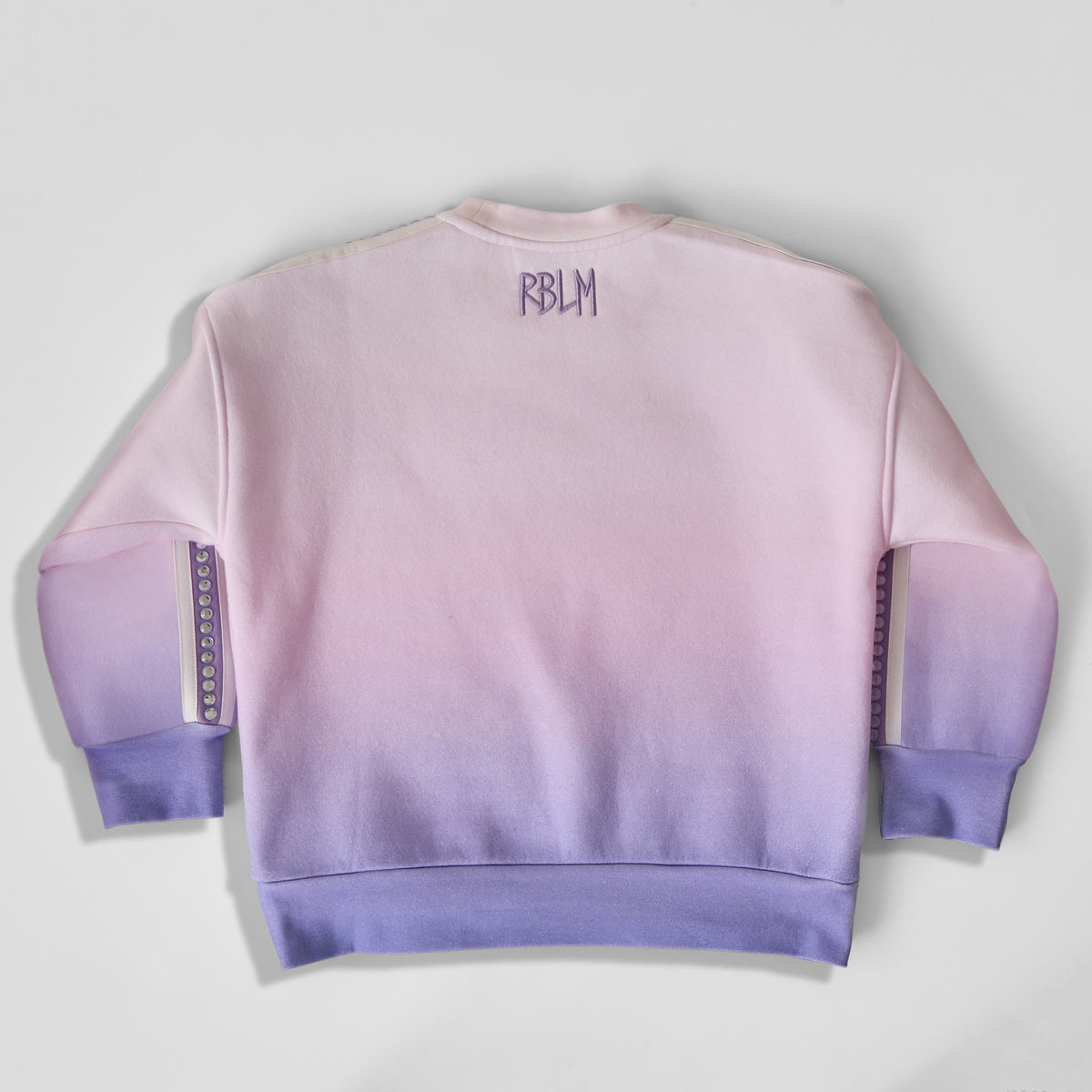 The back of an eco-friendly and comfortable light pink-to-purple gradient crewneck sweatshirt for children, featuring a purple 'RBLM' logo on the upper back.