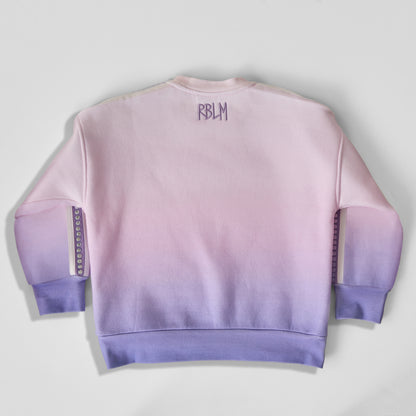 The back of an eco-friendly and comfortable light pink-to-purple gradient crewneck sweatshirt for children, featuring a purple 'RBLM' logo on the upper back.