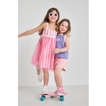 Two girls on a skateboard in eco-friendly dress, tank top, and shorts