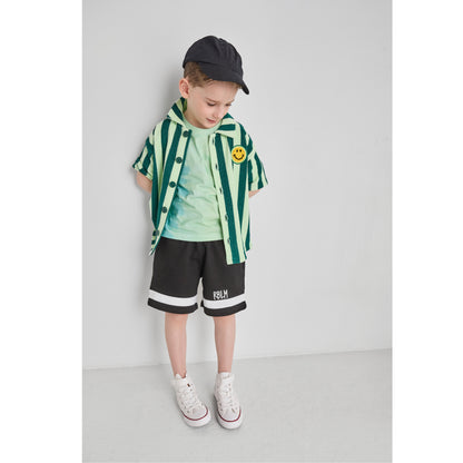 Boy wearing an organic cotton and recycled polyester green striped shirt and black shorts.