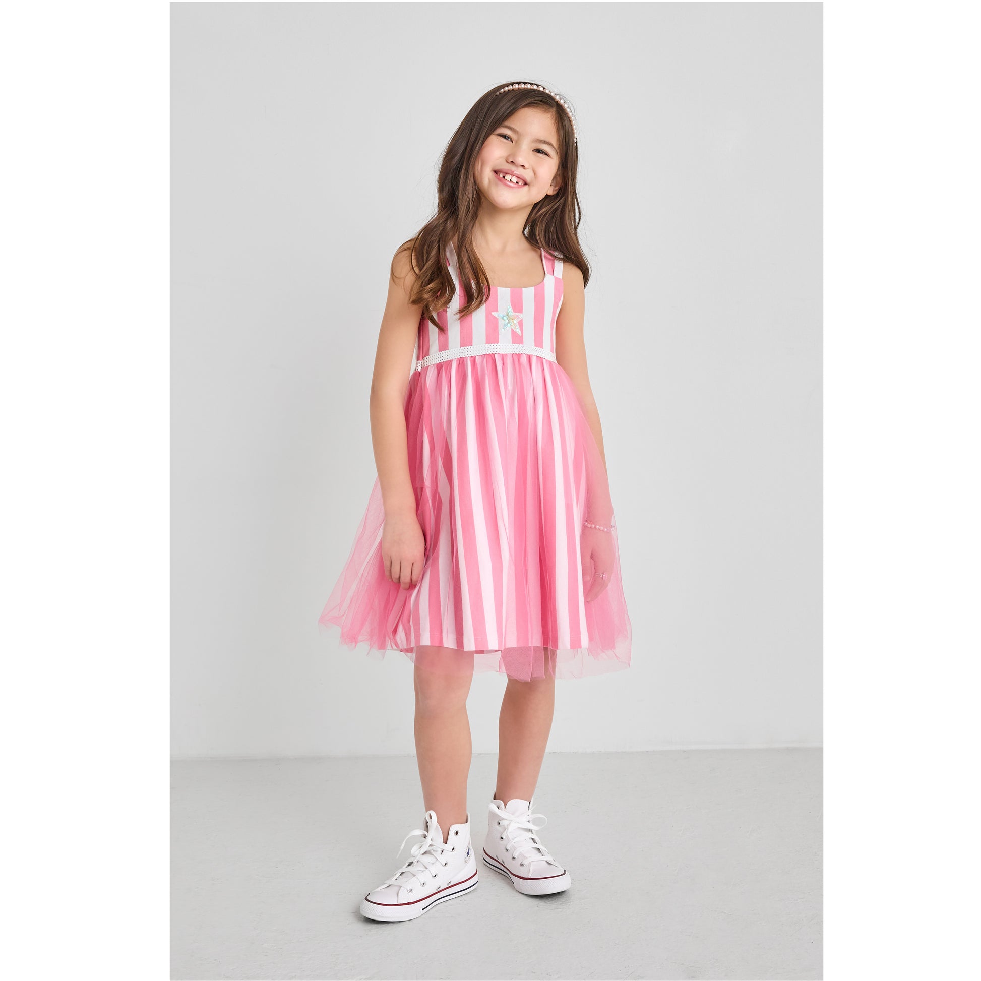 A girl wearing a sustainable pink and white striped tulle dress with recycled sequin star