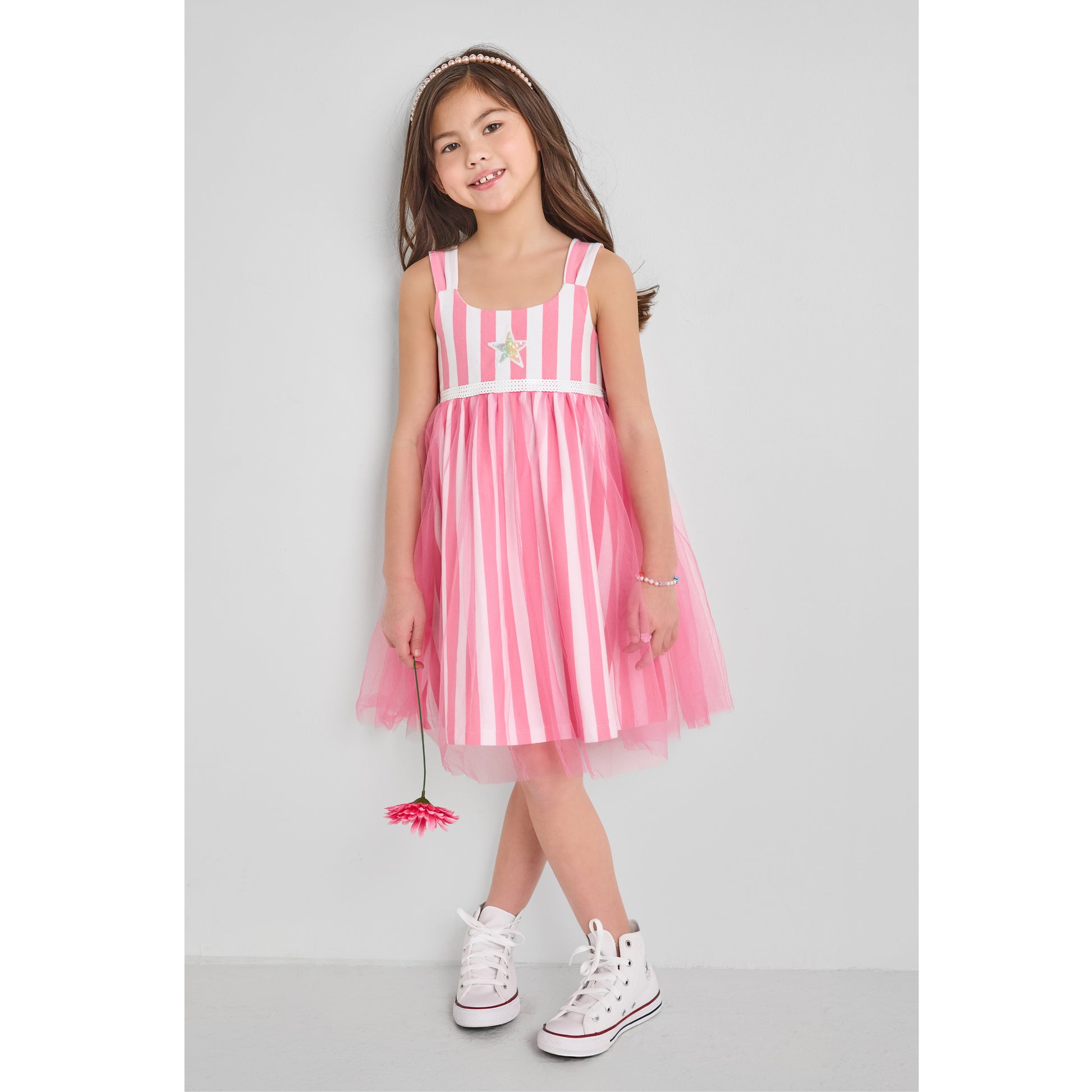A girl wearing an eco-friendly pink and white striped tulle dress holding a daisy