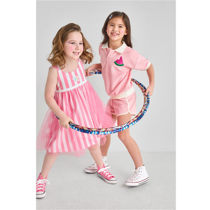 Two girls in cute, bright, sustainable pink outfits with a hula hoop.