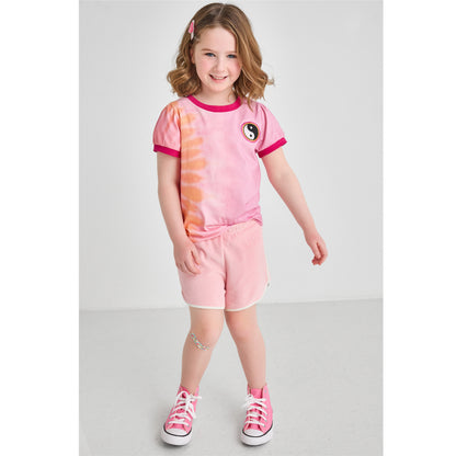 A girl wearing a sustainable pink and orange retro tie-dye t-shirt with pink Terry shorts 