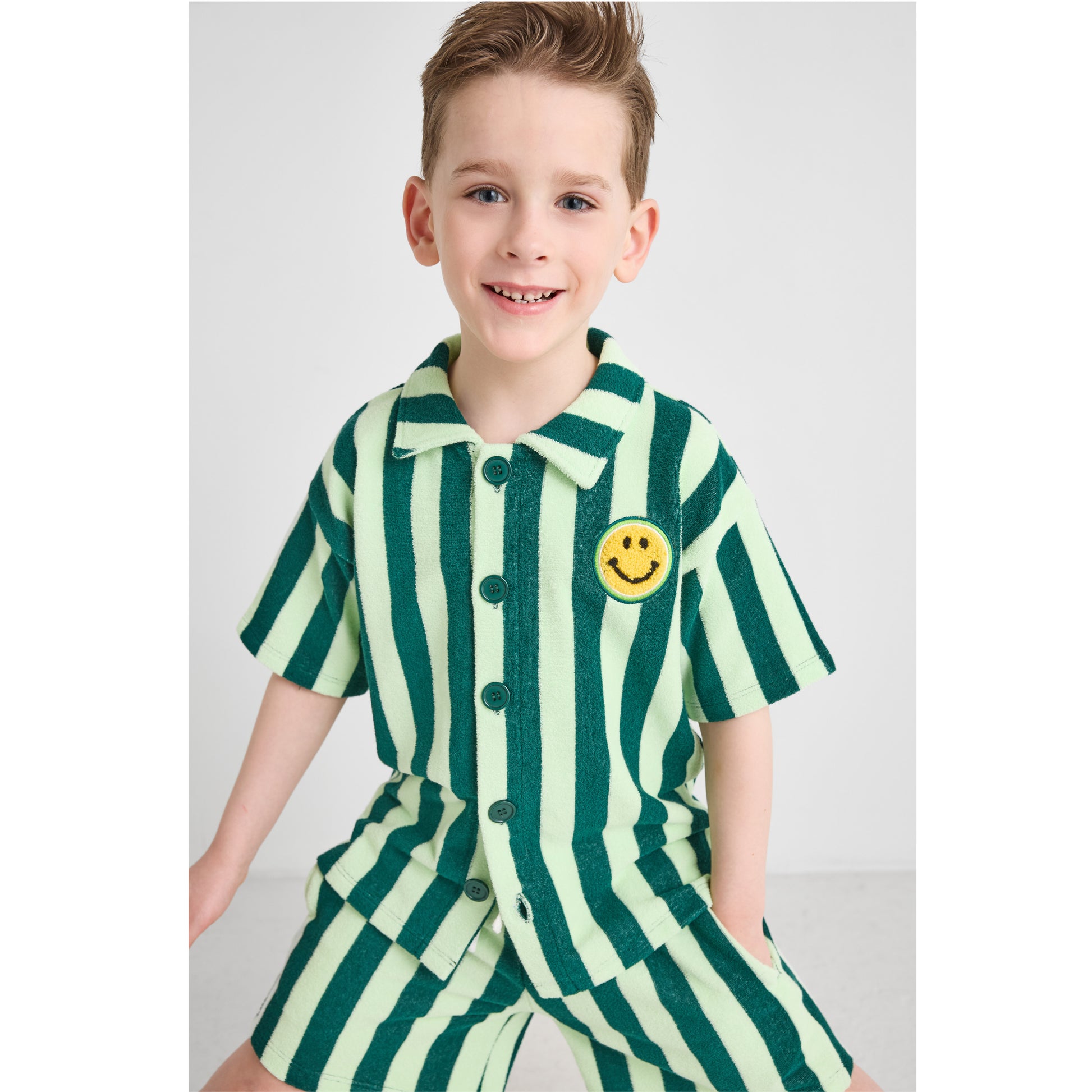 Boy wearing a sustainable green striped outfit with a smiley face 