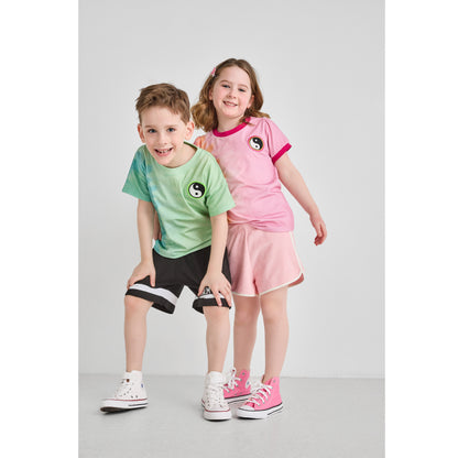 A boy and girl wearing sustainable pink and green tie-dye t-shirts.