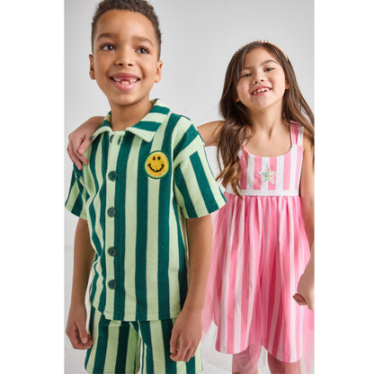 A boy and a girl wearing sustainable green, pink, and white striped outfits.