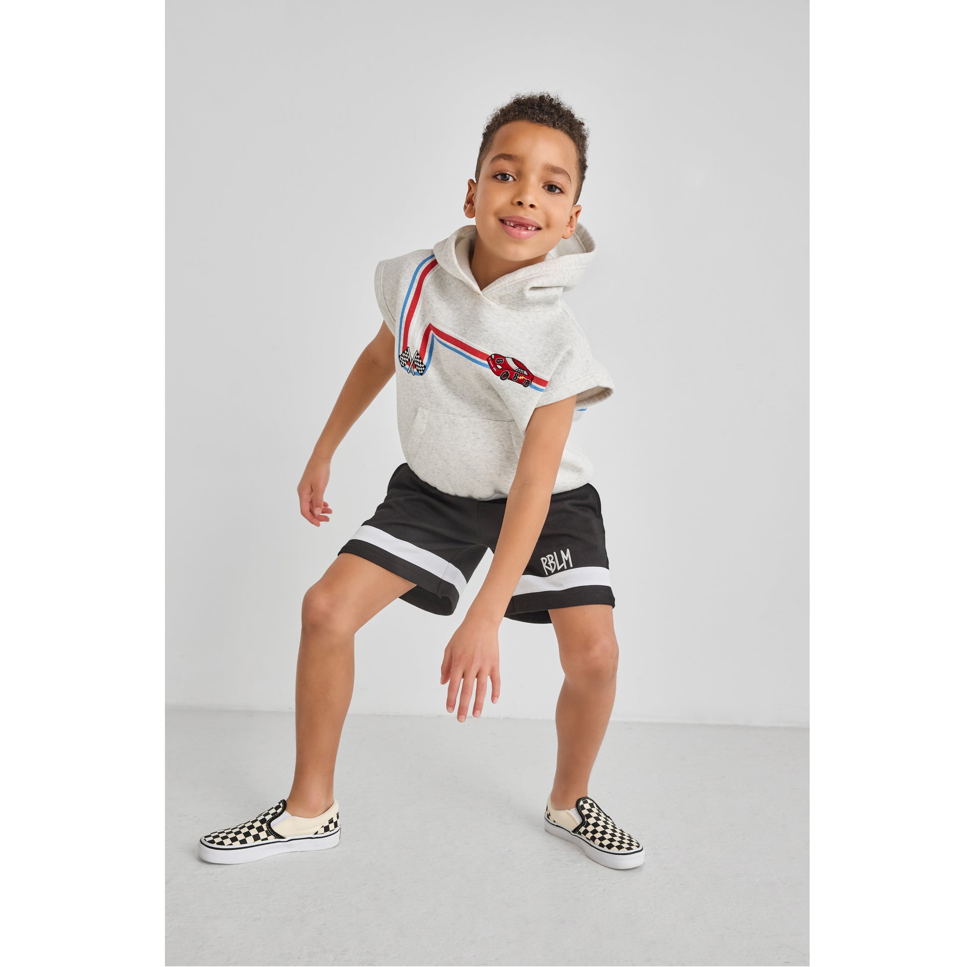 Boy wearing an eco-friendly, fun sleeveless race car hoodie and black shorts.
