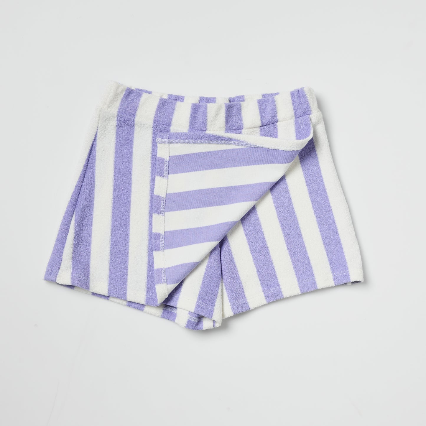 Sustainable kids folded purple and white striped skort on a light gray background