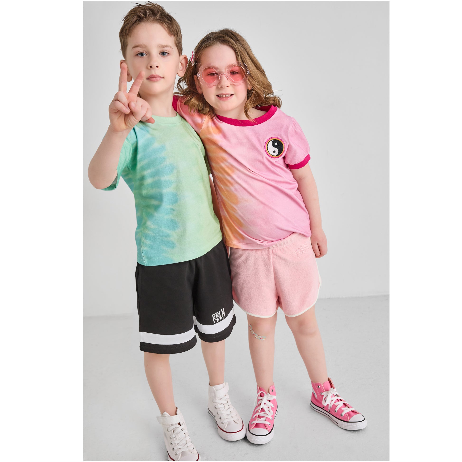 Two children wearing sustainable, retro, tie-dye outfits.