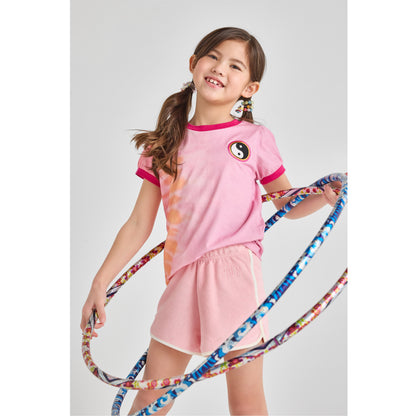 Girl in a sustainable, pink summer outfit with a hula hoop 