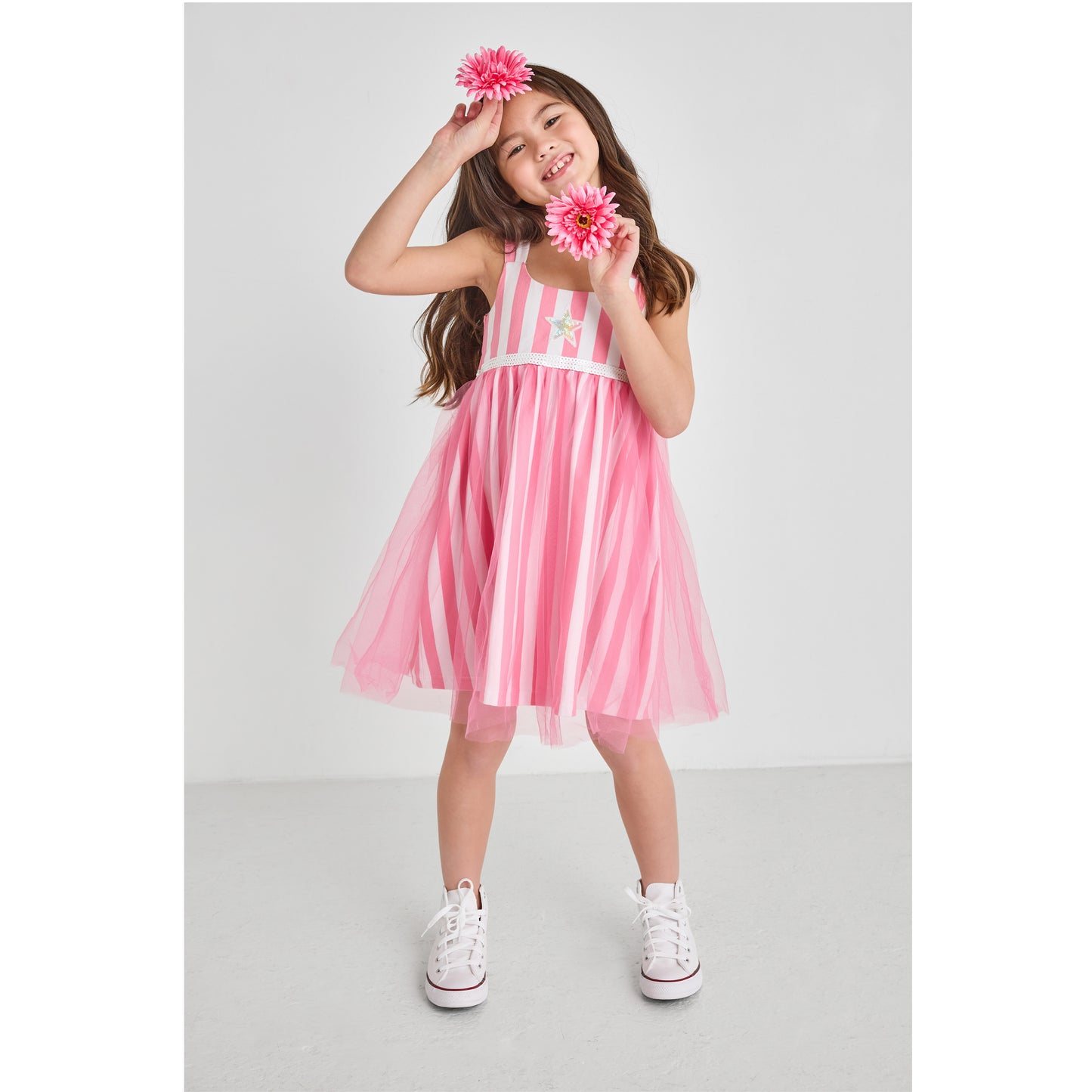 A girl wearing a sustainable pink and white striped tulle dress holding flowers.