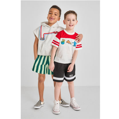 Two children standing together wearing eco-friendly and colorful outfits.