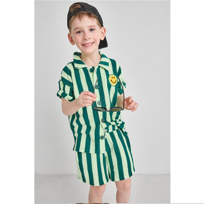 Boy wearing a sustainable bright green striped outfit with a smiley face patch
