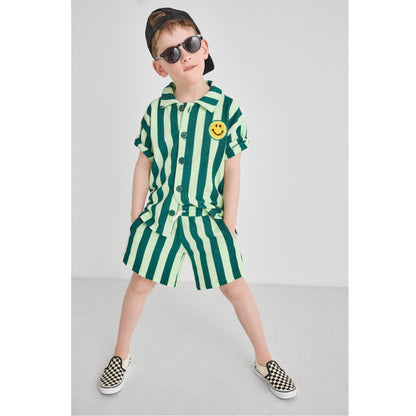Boy wearing a sustainable, fun green striped terry outfit with a smiley face 
