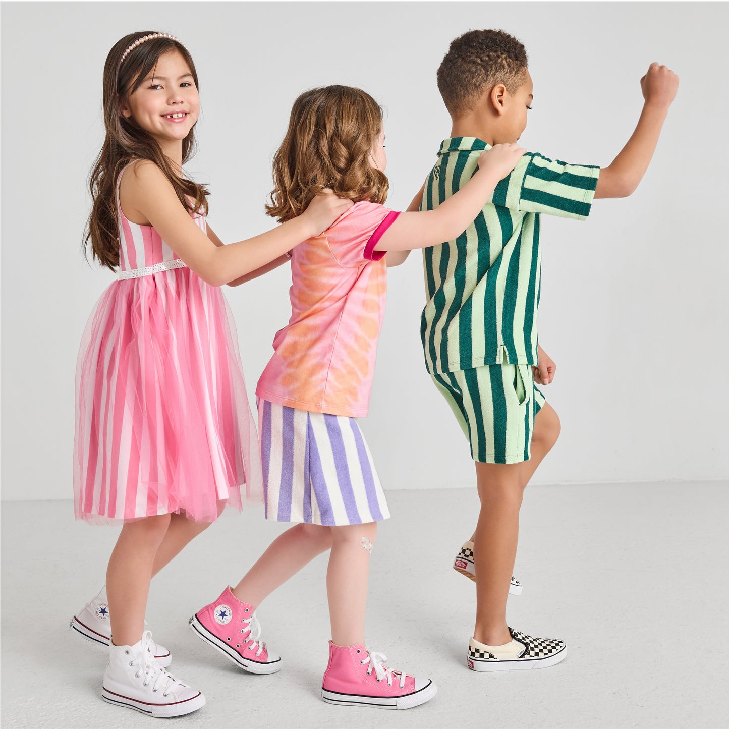 Kids marching, wearing sustainable, colorful striped outfits 