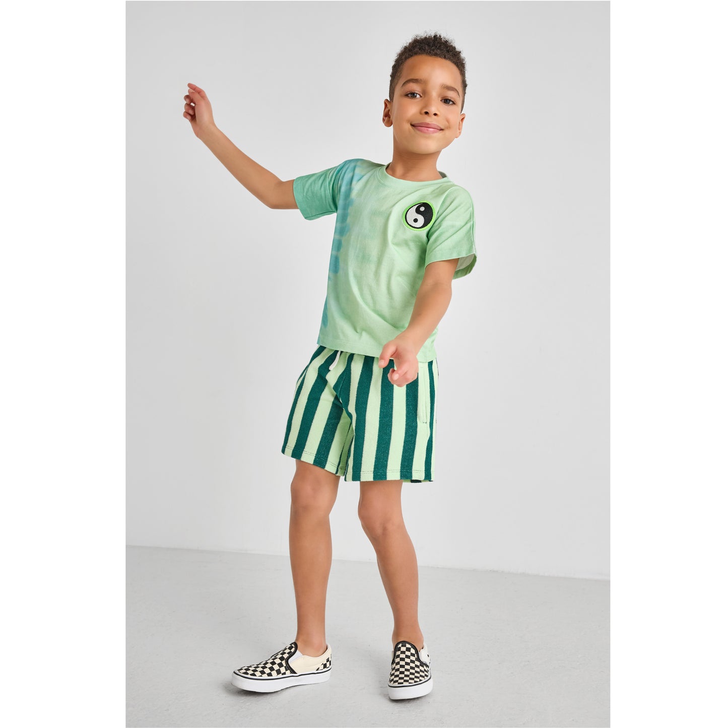 Child wearing an eco-friendly green tie-dye t-shirt and striped terry shorts 