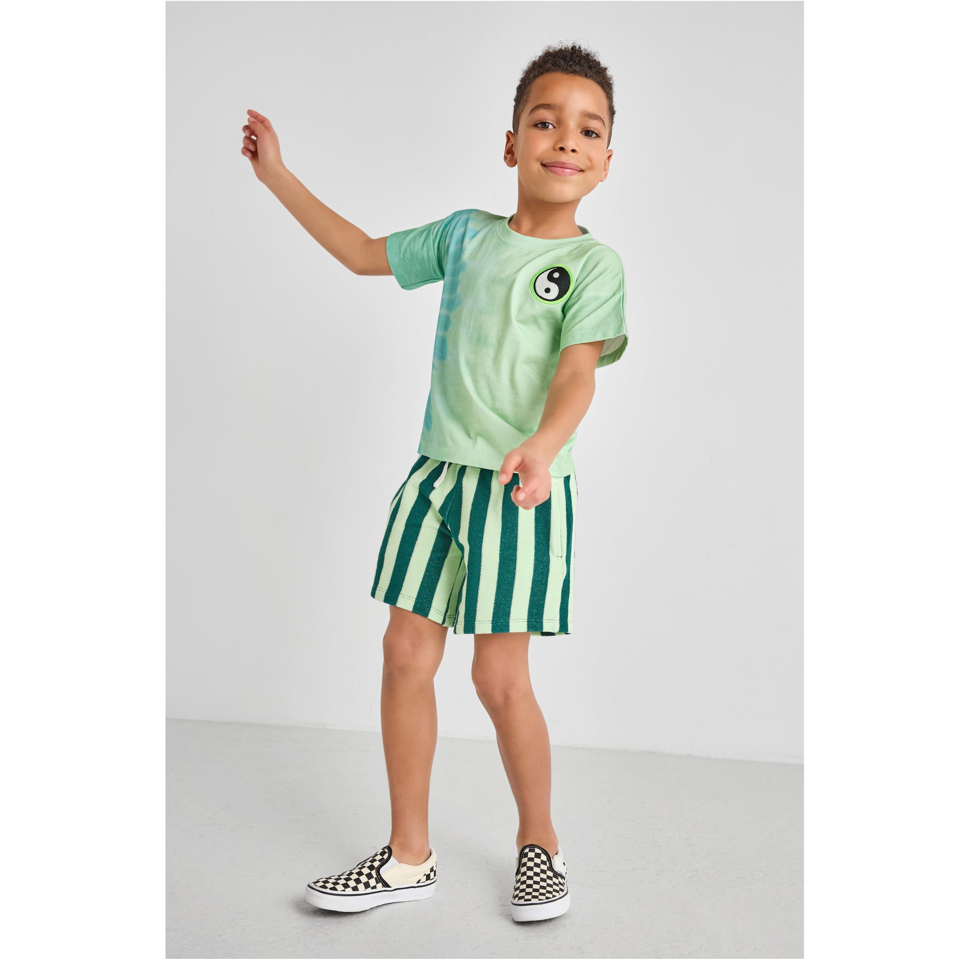 Child wearing an eco-friendly green tie-dye t-shirt and striped terry shorts 