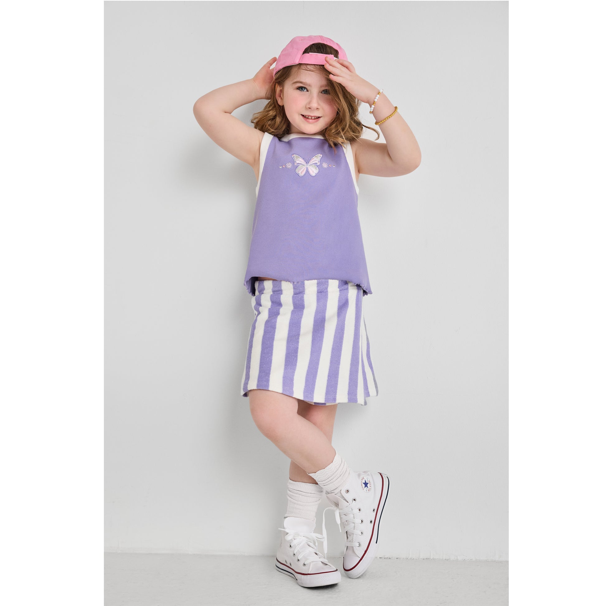 Girl wearing an eco-friendly purple tank top with butterfly embroidery and a purple striped skort