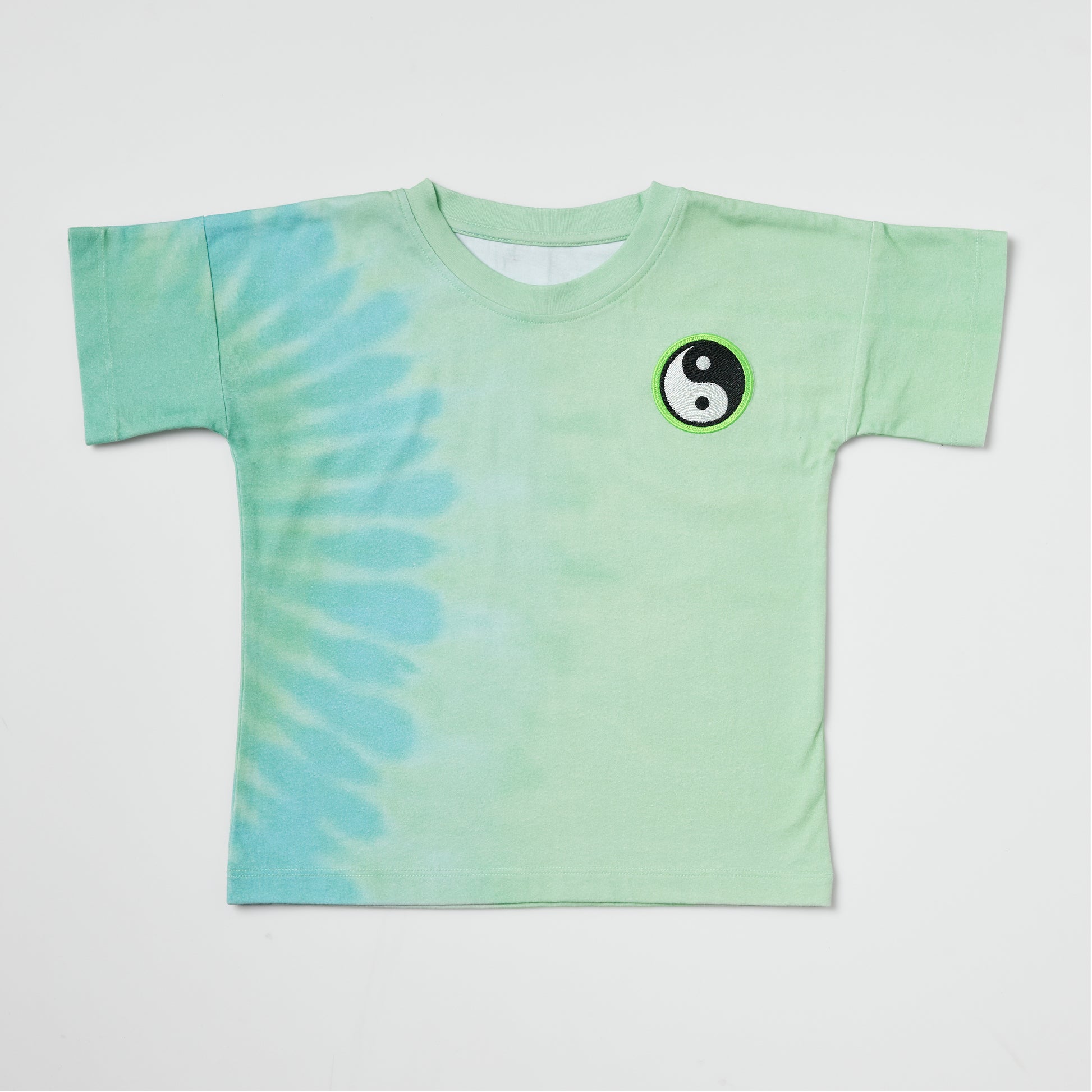 Sustainable kids green tie-dye t-shirt with an embroidered yin yang on a white background