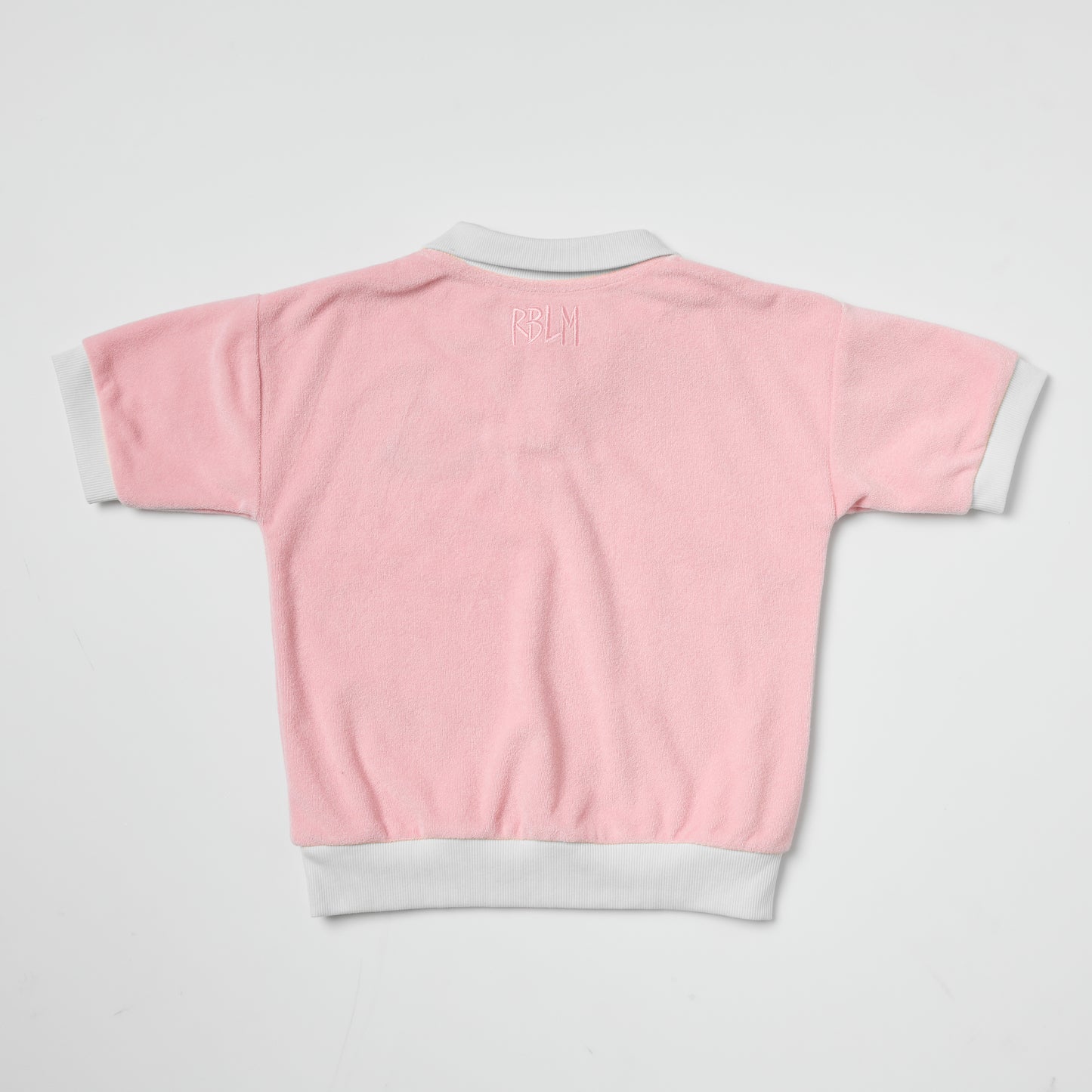 Eco-friendly kids pink terry polo with white trim on a light gray background