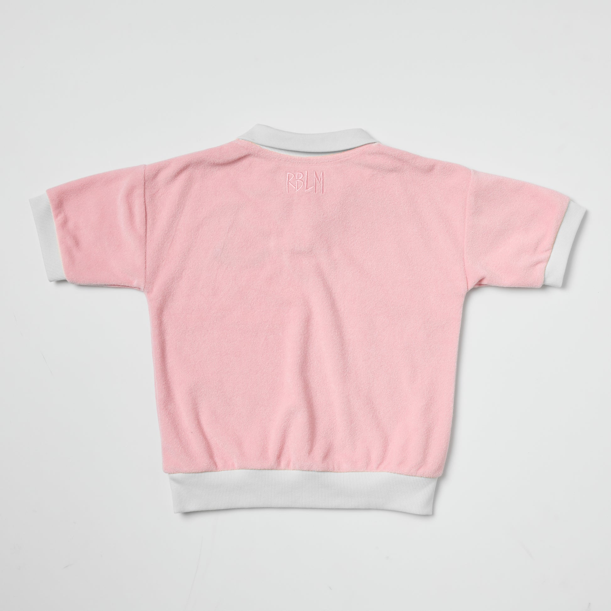 Eco-friendly kids pink terry polo with white trim on a light gray background