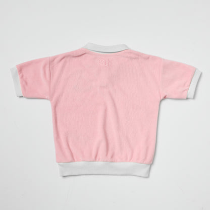 Eco-friendly kids pink terry polo with white trim on a light gray background