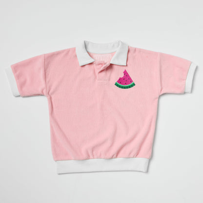 Eco-friendly kids pink and white polo shirt with watermelon embroidery on a light gray background