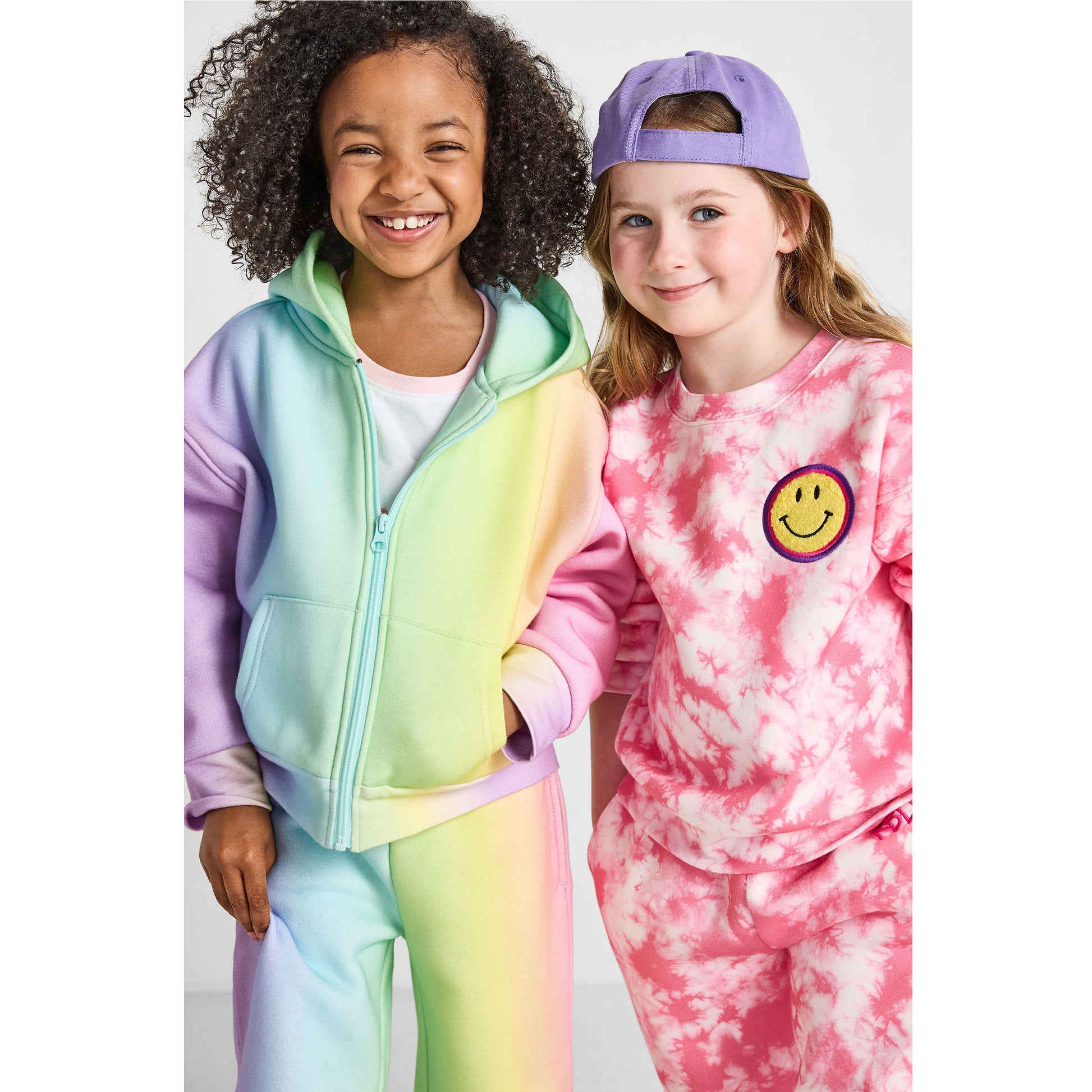 smiling children wearing our sustainable Smiley Tie-Dye Set and Rainbow Wide-Leg Jogger Set